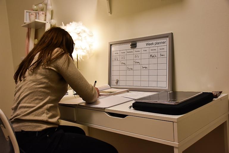 Flicka sitter vid skrivbordet och studerar.